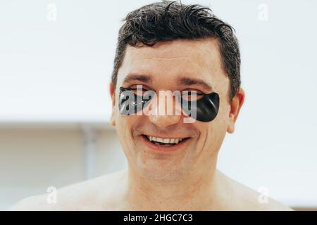 Junger Mann mit schwarzen Flecken auf den Augen in einem Wellness-Schönheitssalon. Das Konzept der Körper- und Gesichtspflege für Männer Stockfoto