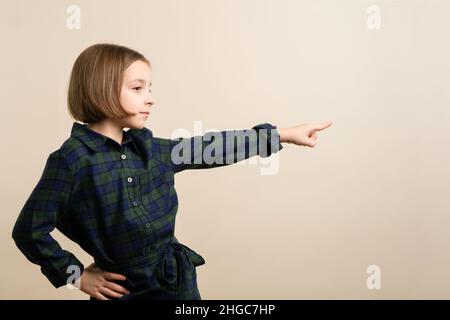 Silent introverted Kid Little Girl 9s das Tragen von kariertem Hemdkleid zeigt die Richtung an. Intelligentes Kind Hat Eine Ausgezeichnete Idee. Ankündigungskonzept. Platz für Werbung kopieren. Stockfoto