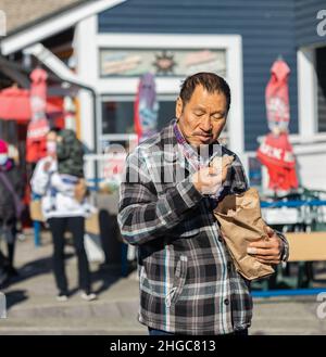 Armer Mann, der in der modernen kapitalistischen Gesellschaft ein Stück Brot isst Stockfoto