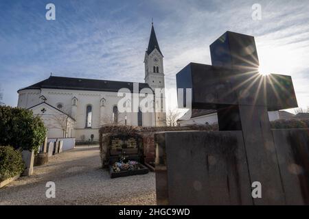 In Der Stadt, Deutschland. 13th Januar 2022. Das Kreuz eines Grabsteins erhebt sich in den Himmel vor der katholischen Kirche St. Nikolaus. Eine vom Bistum München beauftragte Kanzlei will dort am 20. Januar 2022 ein Gutachten zu Missbrauchsfällen vorlegen. Hier wird es auch um den Fall eines Priesters gehen, der in der Pfarrei in der Pfarrei in der Gemeinde von Archling an der Alz ernannt wurde, obwohl er zuvor wegen Kindesmissbrauchs verurteilt worden war. Nach Angaben der Diözese gibt es Hinweise darauf, dass er auch in der Diözese in der Auflehnung war. Kredit: Peter Kneffel/dpa/Alamy Live Nachrichten Stockfoto