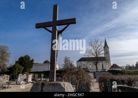 In Der Stadt, Deutschland. 13th Januar 2022. Das Kreuz erhebt sich in den Himmel vor der katholischen Kirche St. Nikolaus. Eine vom Bistum München beauftragte Kanzlei will dort am 20. Januar 2022 ein Gutachten zu Missbrauchsfällen vorlegen. Hier wird es auch um den Fall eines Priesters gehen, der in der Pfarrei in der Pfarrei in der Gemeinde von Archling an der Alz ernannt wurde, obwohl er zuvor wegen Kindesmissbrauchs verurteilt worden war. Nach Angaben der Diözese gibt es Hinweise darauf, dass er auch in der Diözese in der Auflehnung war. Kredit: Peter Kneffel/dpa/Alamy Live Nachrichten Stockfoto