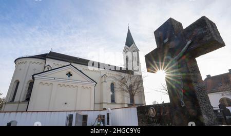 In Der Stadt, Deutschland. 13th Januar 2022. Das Kreuz eines Grabsteins erhebt sich in den Himmel vor der katholischen Kirche St. Nikolaus. Eine vom Bistum München beauftragte Kanzlei will dort am 20. Januar 2022 ein Gutachten zu Missbrauchsfällen vorlegen. Hier wird es auch um den Fall eines Priesters gehen, der in der Pfarrei in der Pfarrei in der Gemeinde von Archling an der Alz ernannt wurde, obwohl er zuvor wegen Kindesmissbrauchs verurteilt worden war. Nach Angaben der Diözese gibt es Hinweise darauf, dass er auch in der Diözese in der Auflehnung war. Kredit: Peter Kneffel/dpa/Alamy Live Nachrichten Stockfoto