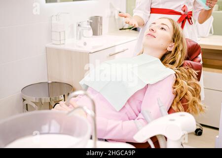 Schöne junge Frau tut Zahnuntersuchung in der Zahnarztpraxis auf einem Zahnstuhl in der Zahnmedizin, Gesundheit Zähne Konzept. Stockfoto