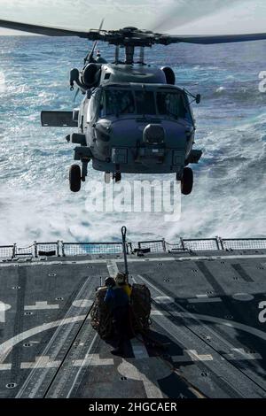 PAZIFISCHER OZEAN (Jan 17, 2022) Boatswain’s Mate Seaman Lissa Herrera, aus Hackensack, N.J., Und Boatswains Mate Seaman Bobby J. Cunningham aus Arlington, Texas, bereitet sich darauf vor, während einer vertikalen Nachschubübung an Bord des Arleigh Burke-Klasse-Lenkflugkörper-Zerstörers USS Gridley (DDG 101) einen Frachthaken an einem MH-60R Sea Hawk-Hubschrauber zu befestigen, der den „Raptors“ des Helicopter Maritime Strike Squadron (HSM) 71 zugewiesen wurde. Die Abraham Lincoln Strike Group befindet sich im geplanten Einsatzbereich der US-Flotte für 7th, um die Interoperabilität durch Allianzen und Partnerschaften zu verbessern und gleichzeitig zu dienen Stockfoto