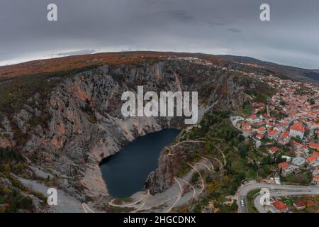 Blauer See, eine große Sinkhole in der Nähe von bekannteren Roten See am Rande des Dorfes Imotski in Südkroatien an einem grauen Tag. Stockfoto