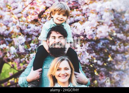 Eltern geben Kindern Huckepack auf dem Land. Mutter Vater und Sohn. Stockfoto