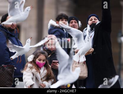 Paris, Frankreich. 19th Januar 2022. Menschen füttern Tauben in der Nähe des Louvre in Paris, Frankreich, 19. Januar 2022. Die COVID-19-Situation in Frankreich verschlechtert sich weiter, da in den letzten 24 Stunden 464.769 neue Fälle entdeckt wurden, wie die Gesundheitsbehörde des Landes am Dienstag mitteilte. Kredit: Gao Jing/Xinhua/Alamy Live Nachrichten Stockfoto