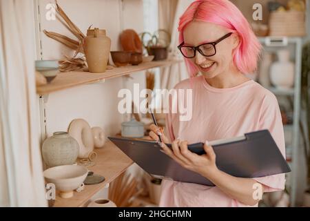 Junge und lächelnde Töpferin, die im Arbeitszimmer Geschäfte macht Stockfoto