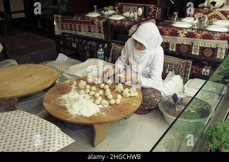 Frau, die den Brotteig für traditionelles türkisches Pide, ein traditionelles Fladenbrot aus der Türkei, in einer Pfanne in einer runden Form zubereitet Stockfoto