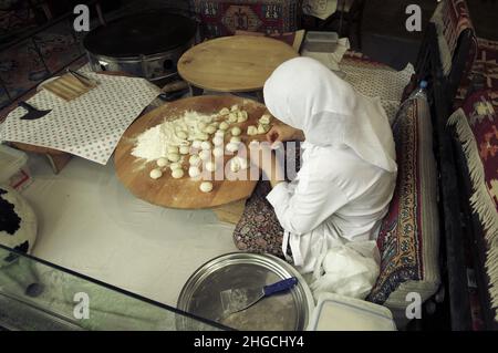 Frau, die den Brotteig für traditionelles türkisches Pide, ein traditionelles Fladenbrot aus der Türkei, in einer Pfanne in einer runden Form zubereitet Stockfoto