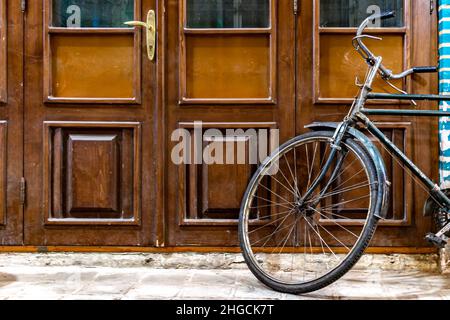 Ein altes Fahrrad neben einer alten Tür Stockfoto