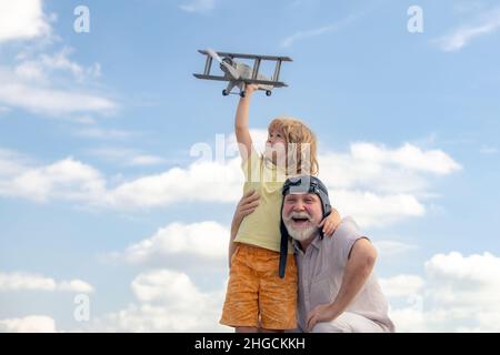 Großvater und Sohn mit Spielzeug-Jetpack-Flugzeug gegen den Himmel. Kind Pilot Flieger mit Flugzeug träumt von Reisen. Stockfoto