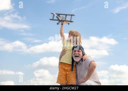 Großvater und Sohn mit Spielzeug-Jetpack-Flugzeug gegen den Himmel. Kind Pilot Flieger mit Flugzeug träumt von Reisen. Stockfoto