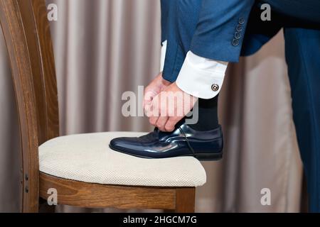 Ein junger Mann bindet die Schnürsenkel seiner Schuhe an - Detail, selektiver Fokus Stockfoto