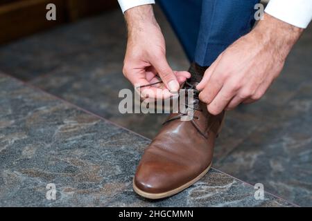 Ein junger Mann bindet die Schnürsenkel seiner Schuhe an - Detail, selektiver Fokus Stockfoto