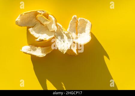 Orangenschale auf gelbem Hintergrund in hellem Licht. Stockfoto