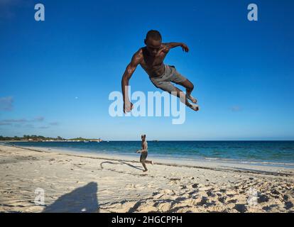 Junge, der Action-akrobatische Sprung eines afrikanischen jungen Mannes ausführt Luftdrehung eines Mannes am Strand in Watamu, Kenia, Afrika Junge männliche Jumping Stockfoto