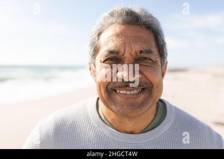 Nahaufnahme eines lächelnden Senioren mit Schnurrbart am Strand während eines sonnigen Tages Stockfoto