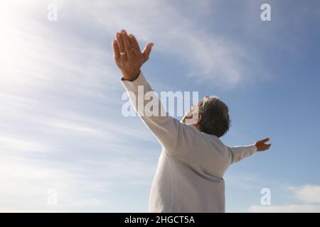 Blick aus der Vogelsicht auf einen sorglosen Senioren mit ausgestreckten Armen unter dem Himmel an einem sonnigen Tag Stockfoto