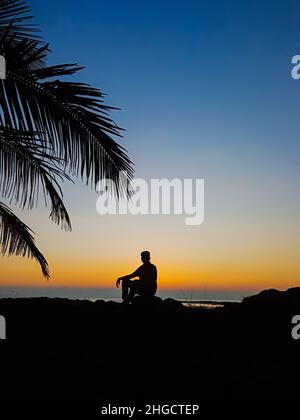Trauriger Mann, Der Auf Dem Felsen Am Strand Sitzt Stockfoto