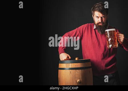 Emotionaler lustiger bärtiger betrunkener Hipster hält Craft-Flaschenbier. Bier in den USA. Lager und dunkles Bier mit Fass oder Fass Bier. Stockfoto