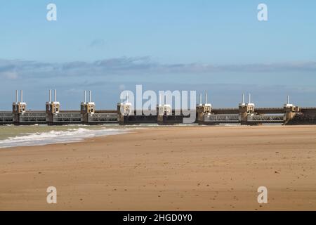 Blick über das Meer zur östlichen Schelde-Sturmflutbarriere in Zeeland mit stürmischem Himmel, dramatischem Sonnenlicht und Sandstrand im Vordergrund. Ooster Stockfoto