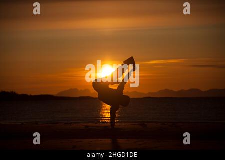 Leute, die Spaß haben, und machen Akrobatik in den Sonnenuntergang am Strand auf den Lofoten Inseln, Norwegen Stockfoto