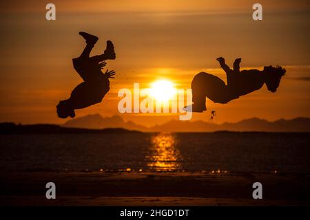 Leute, die Spaß haben, und machen Akrobatik in den Sonnenuntergang am Strand auf den Lofoten Inseln, Norwegen Stockfoto