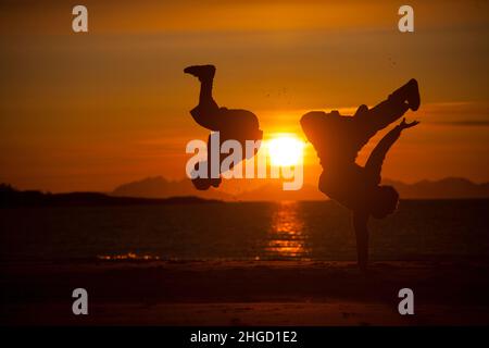 Leute, die Spaß haben, und machen Akrobatik in den Sonnenuntergang am Strand auf den Lofoten Inseln, Norwegen Stockfoto