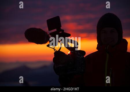 Kameramann in Silhouette mit einem wunderschönen Sonnenuntergang im Hintergrund. Lofoten, Nordnorwegen Stockfoto