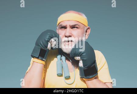 Schöner älterer Mann, der Boxkick übt - Nahaufnahme Porträt. Gesunde Kämpfer Senior alten Mann Boxhandschuhe. Großvater beim Boxtraining Stockfoto