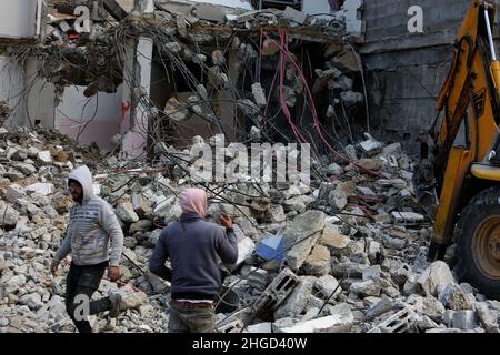 Arbeiter arbeiten daran, die Schutt zu entfernen das zerstörte Gebäude wurde durch Luftangriffe während des israelisch-palästinensischen Konflikts im vergangenen Jahr im Gazastreifen am 19. Januar 2022 zerstört. Stockfoto