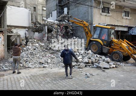 Arbeiter arbeiten daran, die Schutt zu entfernen das zerstörte Gebäude wurde durch Luftangriffe während des israelisch-palästinensischen Konflikts im vergangenen Jahr im Gazastreifen am 19. Januar 2022 zerstört. Stockfoto