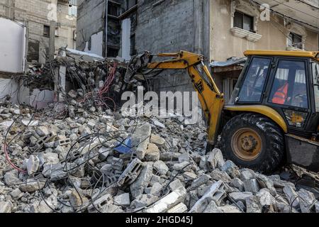 Arbeiter arbeiten daran, die Schutt zu entfernen das zerstörte Gebäude wurde durch Luftangriffe während des israelisch-palästinensischen Konflikts im vergangenen Jahr im Gazastreifen am 19. Januar 2022 zerstört. Stockfoto