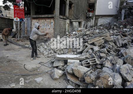 Arbeiter arbeiten daran, die Schutt zu entfernen das zerstörte Gebäude wurde durch Luftangriffe während des israelisch-palästinensischen Konflikts im vergangenen Jahr im Gazastreifen am 19. Januar 2022 zerstört. Stockfoto