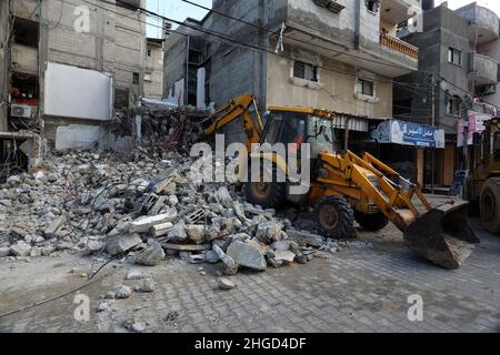 Arbeiter arbeiten daran, die Schutt zu entfernen das zerstörte Gebäude wurde durch Luftangriffe während des israelisch-palästinensischen Konflikts im vergangenen Jahr im Gazastreifen am 19. Januar 2022 zerstört. Stockfoto