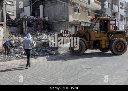 Arbeiter arbeiten daran, die Schutt zu entfernen das zerstörte Gebäude wurde durch Luftangriffe während des israelisch-palästinensischen Konflikts im vergangenen Jahr im Gazastreifen am 19. Januar 2022 zerstört. Stockfoto