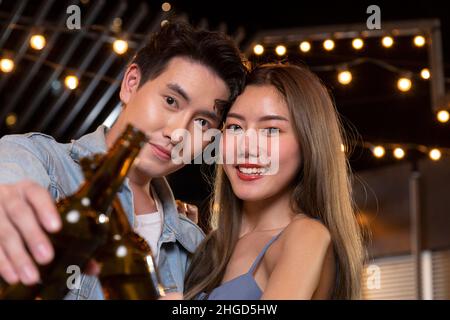 Glücklich asiatische Teenager Paar Mann und Frau verliebt Bier Alkohol trinken und Toasting Flasche in der Feier Partei. Junge glückliche Paar Liebe und romantisch Stockfoto