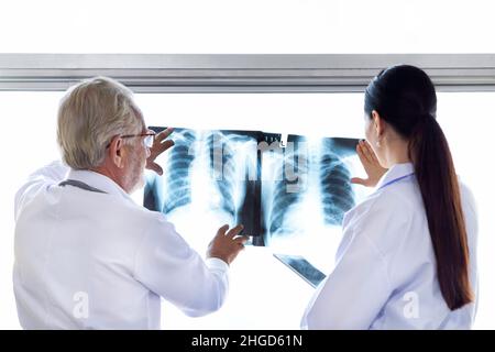 Ärzte des medizinischen Chirurgen schauen sich den Röntgenfilm an und besprechen die Behandlung vor der Operation im Krankenhaus. Stockfoto