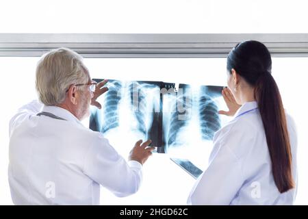 Ärzte des medizinischen Chirurgen schauen sich den Röntgenfilm an und besprechen die Behandlung vor der Operation im Krankenhaus. Stockfoto