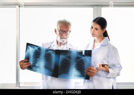 Ärzte des medizinischen Chirurgen schauen sich den Röntgenfilm an und besprechen die Behandlung vor der Operation im Krankenhaus. Stockfoto