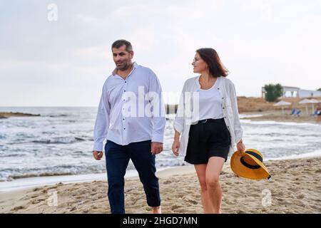 Ein glückliches Paar mittleren Alters, das am Strand zusammen läuft. Stockfoto