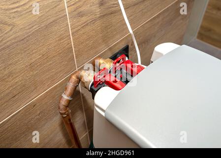 Kupferrohre liefern Wasser an einen stagnierenden Wasserenthärter im Heizraum. Stockfoto