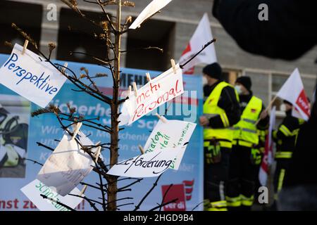 29. Dezember 2021, Sachsen-Anhalt, Halle (Saale): Ein abgebrannter Weihnachtsbaum mit Forderungen an die Stadt steht vor dem gemeinderat. Feuerwehrleute nutzen sie, um gegen „geheime Kostensenkungsmaßnahmen“ und mangelnde Wertschätzung der Stadt zu protestieren. Foto: Kevin Meyer/dpa-Zentralbild/dpa Stockfoto