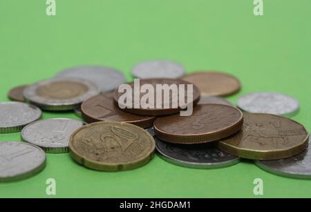 Münzen verschiedener Länder. Eine Streuung von Münzen auf grünem Hintergrund. Geringe Schärfentiefe Stockfoto