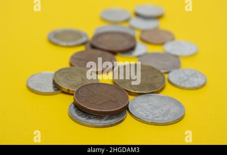 Münzen verschiedener Länder. Eine Streuung von Münzen auf dem gelben Hintergrund. Geringe Schärfentiefe, Kopierbereich Stockfoto