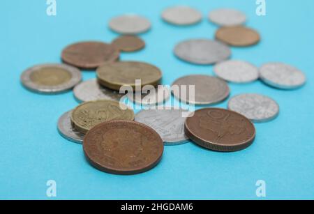 Münzen verschiedener Länder. Eine Streuung von Münzen auf dem blauen Hintergrund. Geringe Schärfentiefe, Kopierbereich Stockfoto