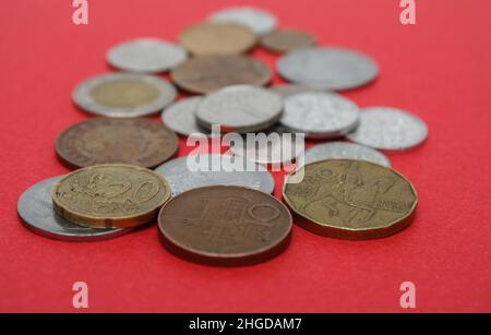 Münzen verschiedener Länder. Eine Streuung von Münzen auf dem roten Hintergrund. Geringe Schärfentiefe, Kopierbereich Stockfoto