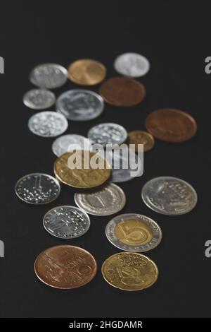 Münzen verschiedener Länder. Eine Streuung von Münzen auf schwarzem Hintergrund. Geringe Schärfentiefe Stockfoto