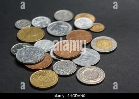 Münzen verschiedener Länder. Eine Streuung von Münzen auf schwarzem Hintergrund. Geringe Schärfentiefe Stockfoto